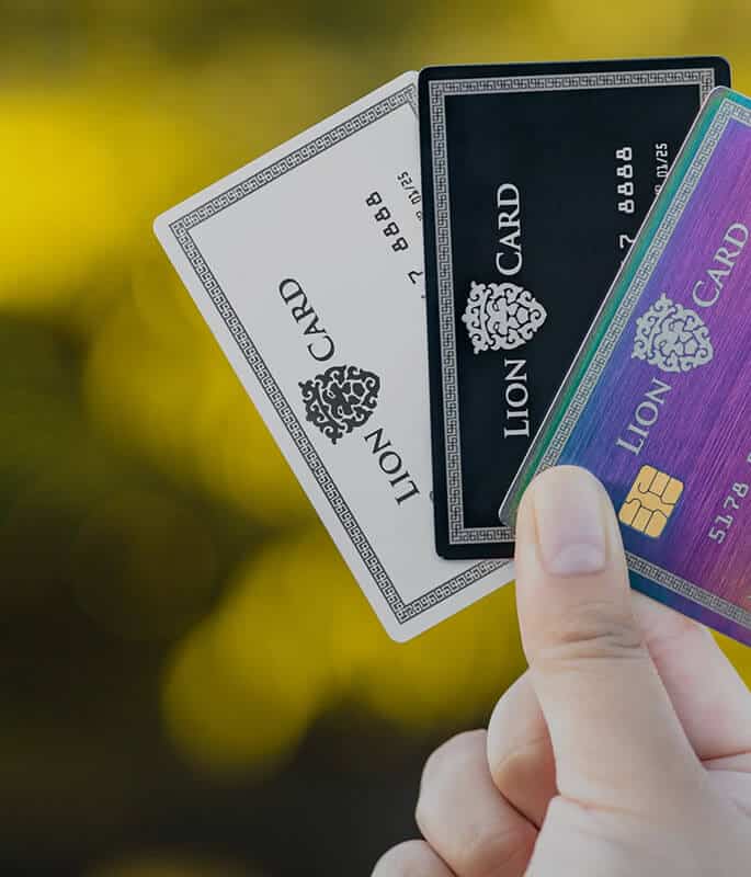 1. Clear images of three Lion Card credit cards in hand, showcasing different designs for financial flexibility and rewards.